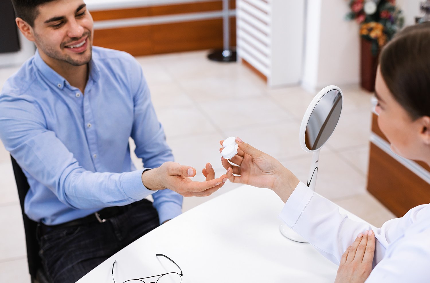 optician-giving-container-with-contact-lenses-to-customer small